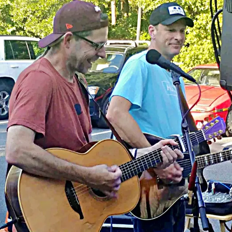 Live acoustic music performance by two guitarists at an outdoor brewery event.